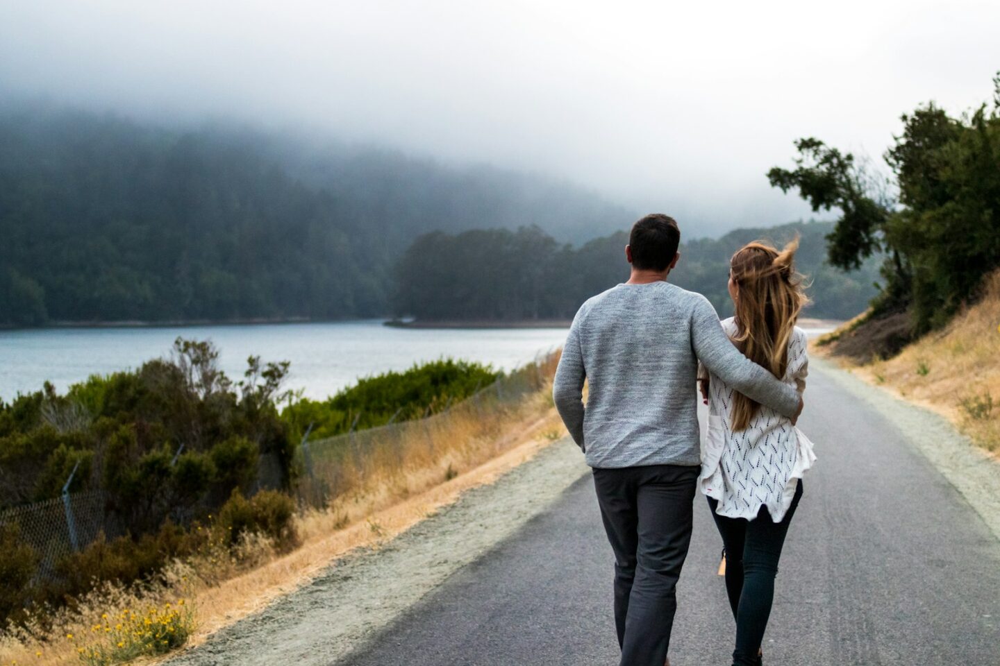 Couple walking together along a misty lakeside road, couples counseling in Alaska