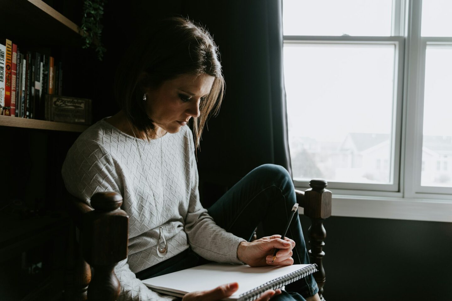 Woman journaling in a calm, sunlit room, somatic and emotionally focused therapy Anchorage