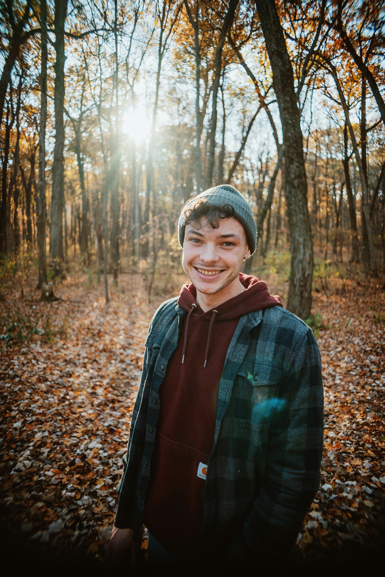 Smiling teen in a beanie and flannel on a forest trail, teen therapy in Anchorage