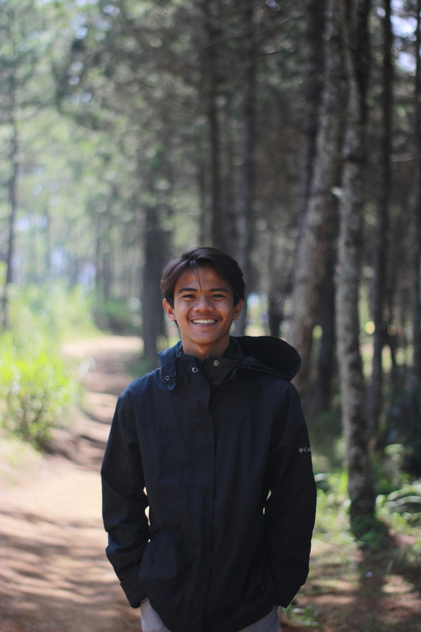 Smiling teen boy in a hoodie on a wooded trail, Anchorage teen therapy